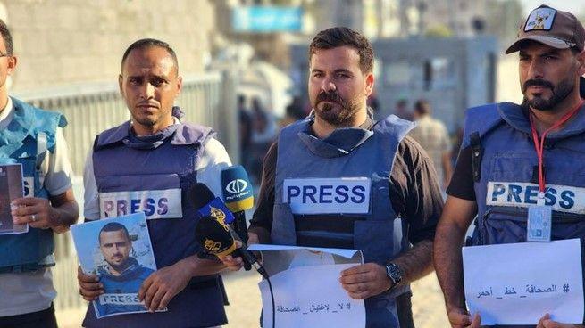 أربعة صحفيين فلسطينيين من غزة يحملون صوراً لزميلهم حمزة مرتجى الذي قتل في الغارات الإسرائيلية على القطاع.