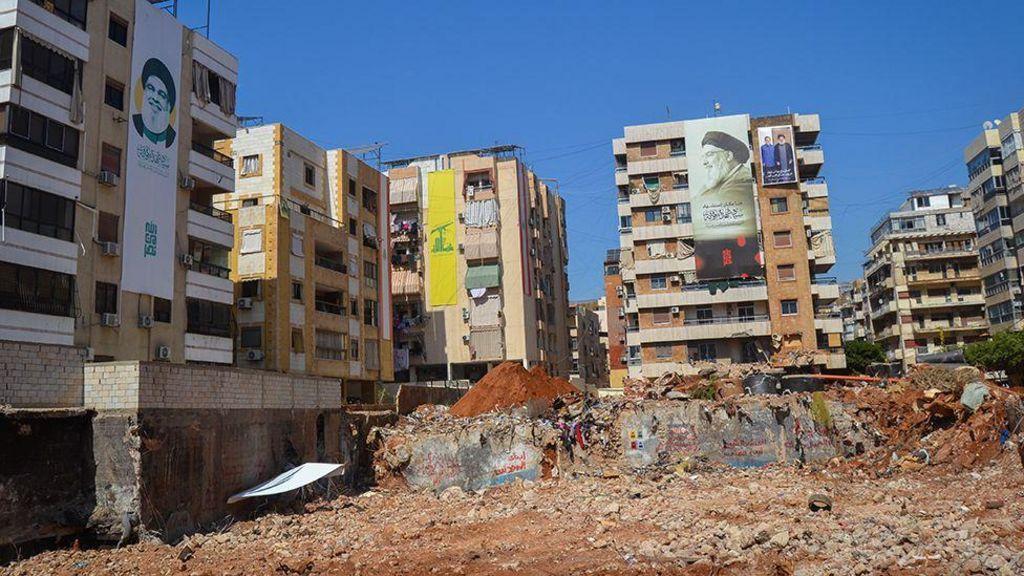 صورة لموقع هدمته الغارات الإسرائيلية، وحوله مبان مغطاة بلافتات إحداها صفراء اللون بشعار حزب الله، ولافتات أخرى تحمل صورة مكبرة لزعيم حزب الله الراحل حسن نصر الله.