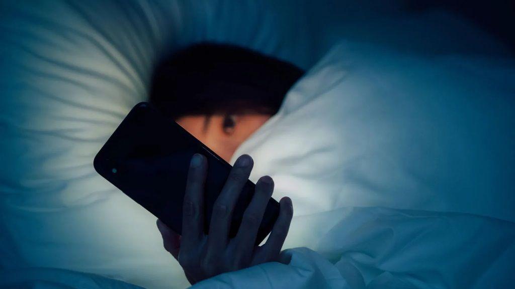 شابة تستخدم هاتفها الذكي قبل الخلود للنوم