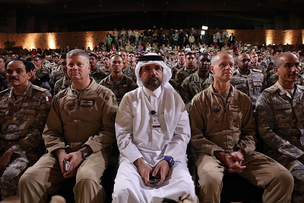 عسكريون أمريكيون وقطريون يستعمون إلى الرئيس الأمريكي دونالد ترامب وهو يتحدث على خشبة المسرح خلال جولة في قاعدة العديد الجوية في 15 مايو 2025، في العاصمة القطرية الدوحة.