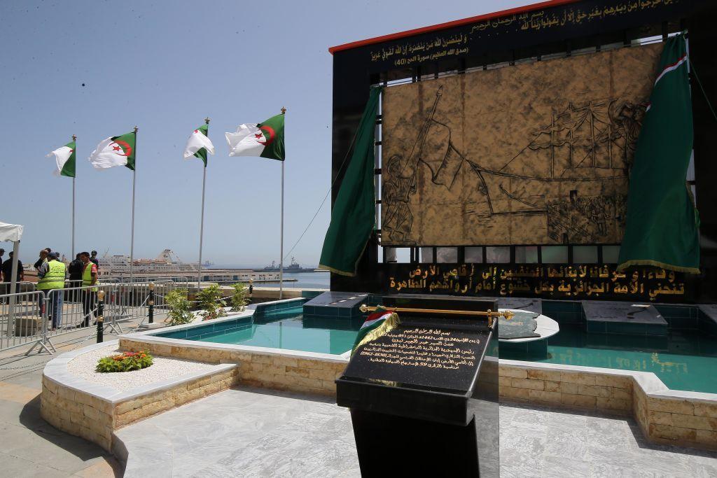 أعلام جزائرية ولوحة رخامية رمزية بجوار النصب التذكاري في الجزائر العاصمة، للجزائريين الذين نفوا إلى كاليدونيا الجديدة، بتاريخ 5 يوليو/تموز 2021.
