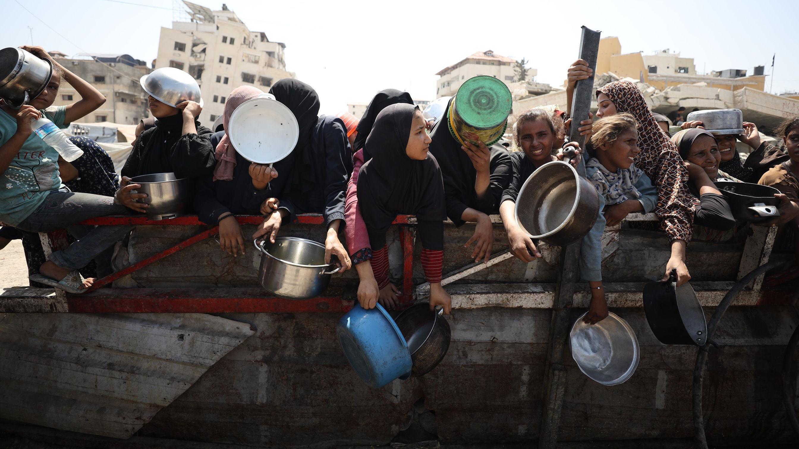 يتلقى فلسطينيون، بمن فيهم أطفال، وجبات ساخنة، توزعها منظمات خيرية، في ظل معاناة الناس من أجل الحصول على الغذاء بسبب الحصار الغذائي الإسرائيلي في مدينة غزة، غزة، في 23 أغسطس/آب 2025. 