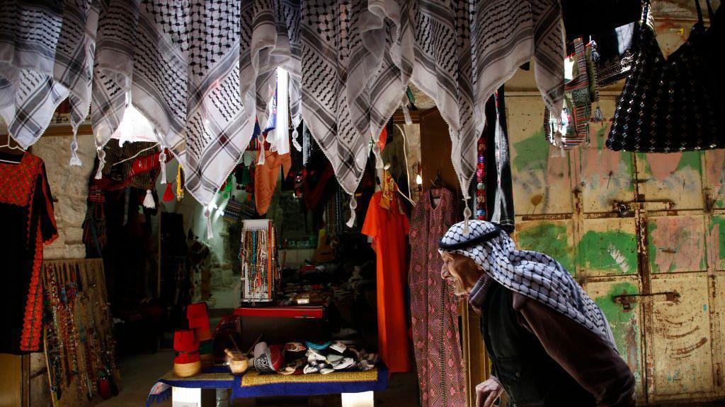 رجل فلسطيني مسن يسير في البلدة القديمة في مدينة الخليل بالضفة الغربية المحتلة.