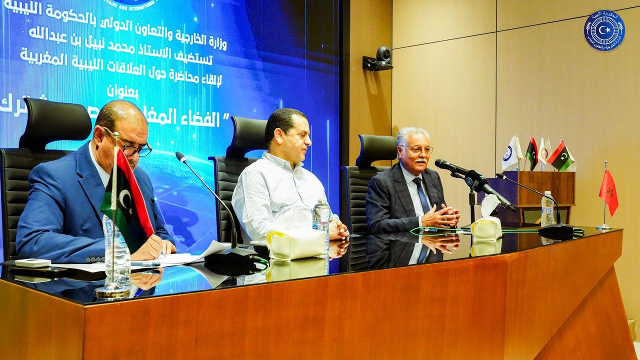 May be an image of ‎3 people, dais, newsroom and ‎text that says '‎ToBA N ANG Aik بالحكومة اللسة الخارجية والتعاونُ الدولى وزارة نبيل بن عبدالله تستظيف الاستاط محمد العلاقات الليبية المغربية لإلقاء محاضرة دول بعنوان الفضاء المغا C*‎'‎‎