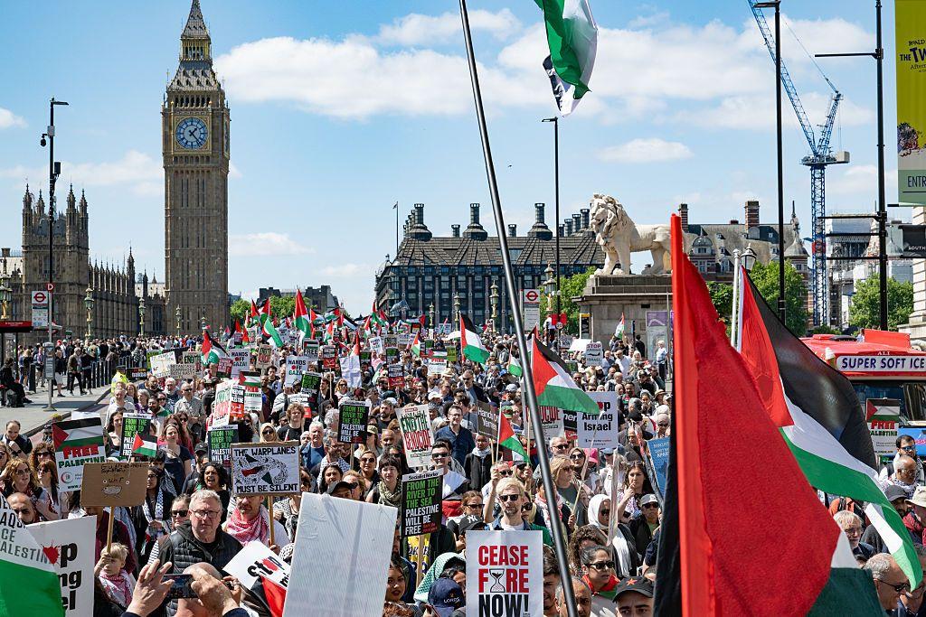 يحمل مشاركون في المظاهرة العلم الفلسطيني (أسود، أبيض، أخضر، ومثلث أحمر). أعداد كبيرة تشارك في المظاهرة ويحملون يافطات كتب عليها باللغة الإنجليزية دعوات لوقف إطلاق النار والحرية للفلسطينيين. المظاهرة كانت نهاراً وفي الخلفية ساعة بج بن.