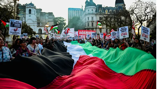 مؤيدون للفلسطينيين يحملون علماً فلسطينياً ضخماً خلال مظاهرة تضامناً مع 