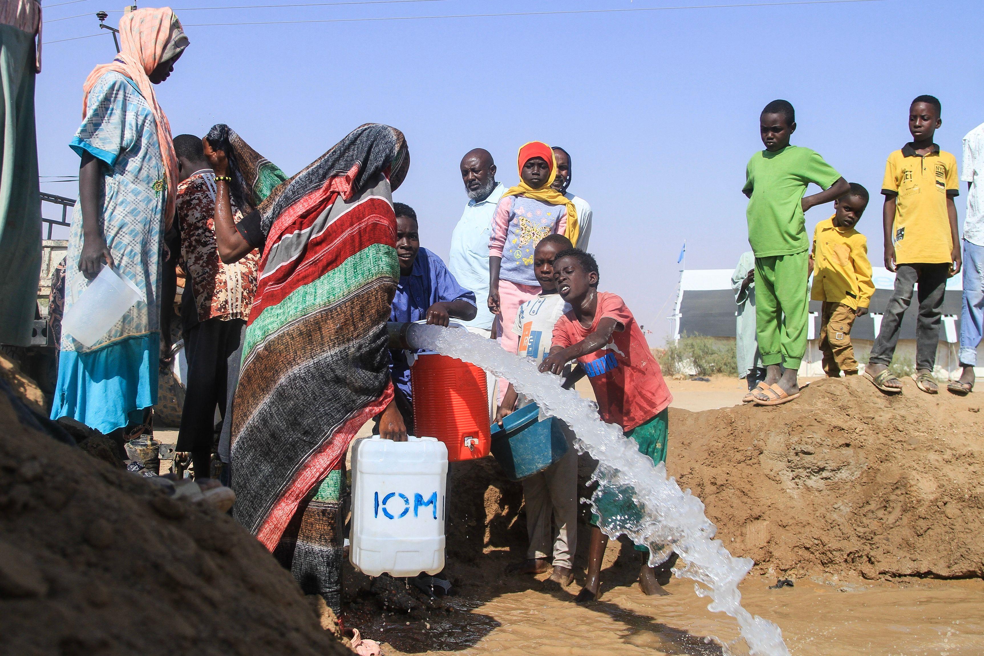 سودانيون نزوحوا من الفاشر في دارفور يملأون عبوات المياه في مخيم في بلدة الدبة شمالي السودان في 21 نوفمبر/تشرين الثاني 2025.