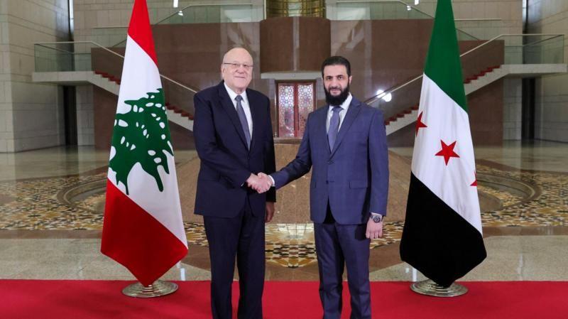 الرئيس السوري أحمد الشرع يصافح رئيس الوزراء اللبناني نجيب ميقاتي أثناء لقائهما في يناير/كانون الثاني في دمشق.
