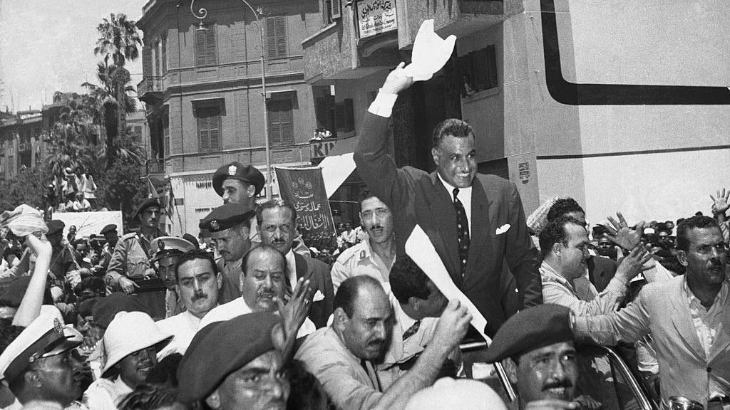 استُقبل الرئيس المصري جمال ناصر بحفاوة بالغة لدى عودته إلى القاهرة من الإسكندرية خلال أزمة السويس. في هذه الصورة بالأبيض والأسود، حمله أنصاره على أكتافهم ولوّح بمنديل أبيض. وكان يرتدي بدلة.