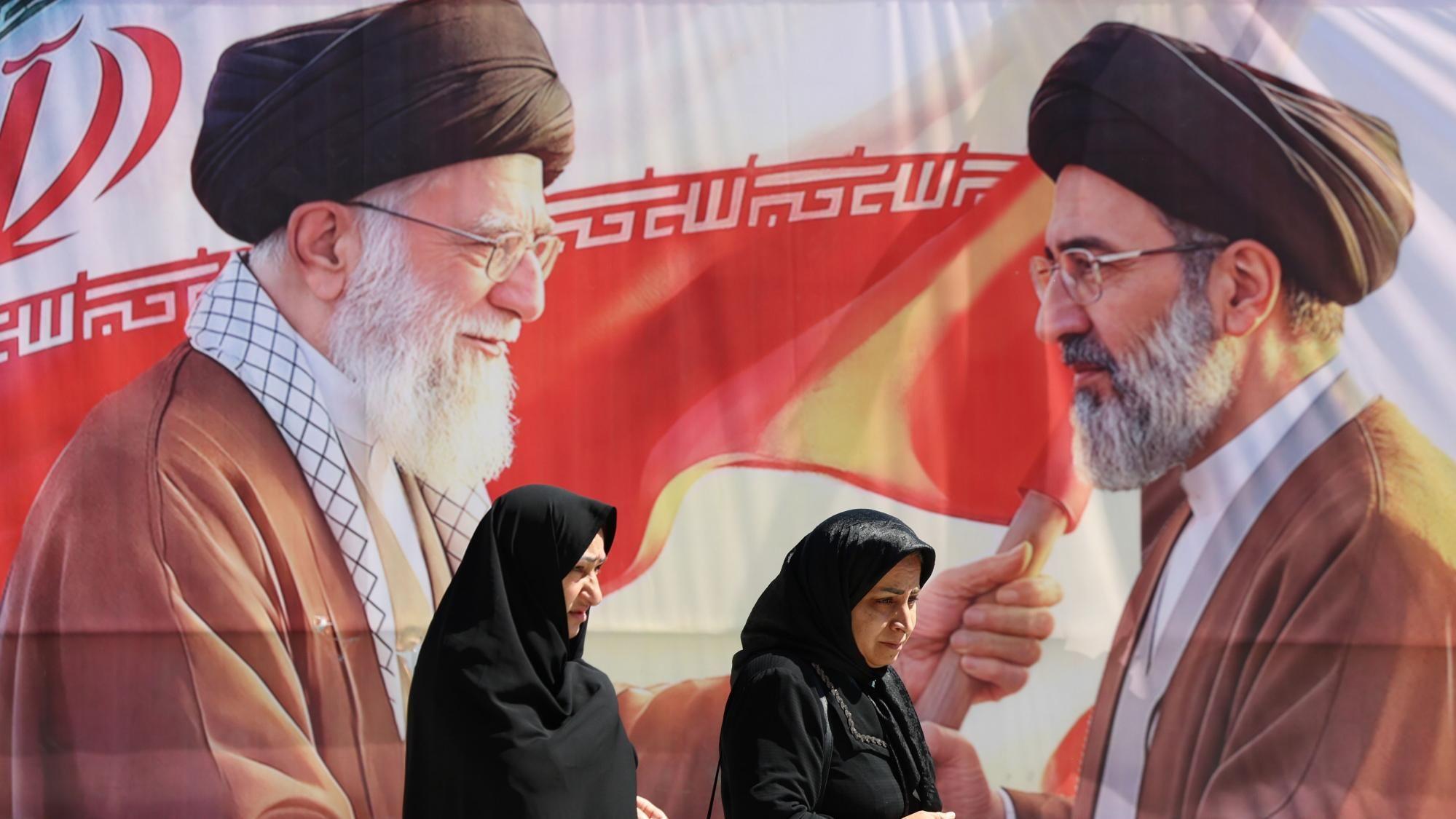 سيدتان إيرانيتان تمران أمام صورة عملاقة للمرشد الجديد للجمهورية الإسلامية في إيران مجتبى خامنئي (يمين) ووالده على الخامنئي (يسار)