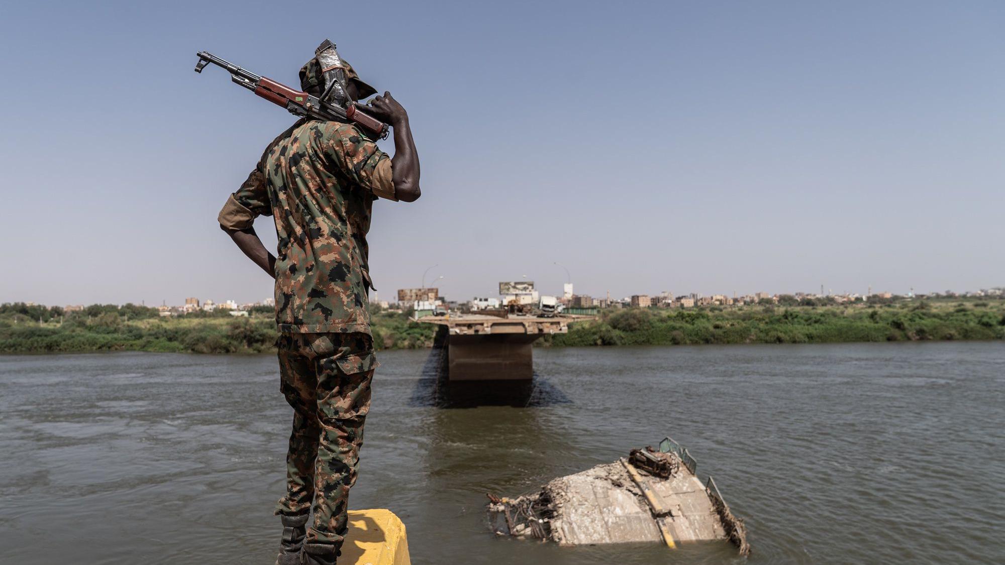 جندي من القوات المسلحة السودانية يقف على حافة جسر شمبات المُدمَّر، الذي كان يربط أم درمان بحي بحري في الخرطوم على الضفة المقابلة لنهر النيل.