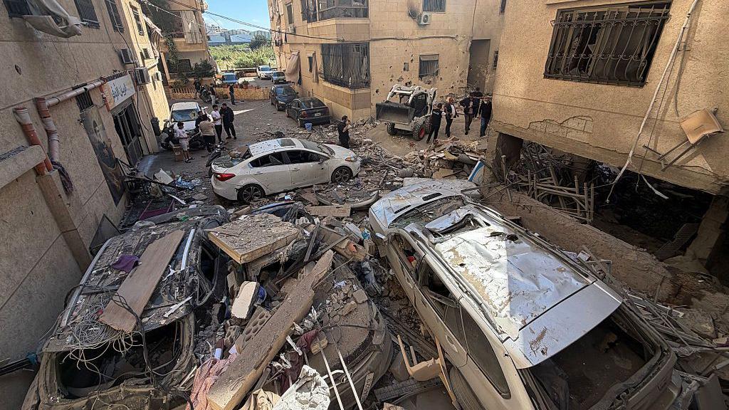 عمال إنقاذ وسكان محليون يتفقدون الأضرار التي لحقت بمبنى إثر غارة إسرائيلية على منطقة الشويفات